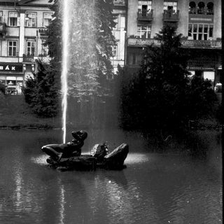 A statue of a child in a boat under a fountain.