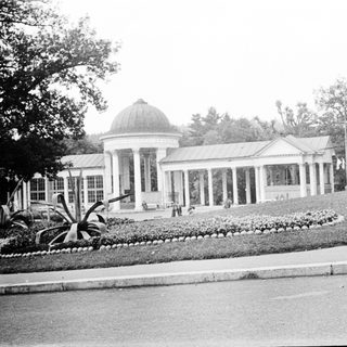 Neoclassical pavilion in landscaped park setting.