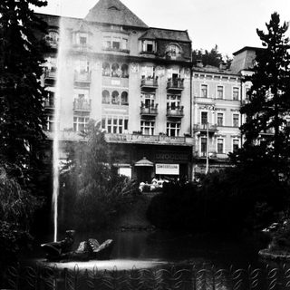 Elegant historic hotel with fountain in landscaped garden.