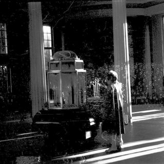 Vintage interior with glass display case, elderly person in dimly lit hall.