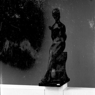 Modern bronze sculpture of seated woman figure.