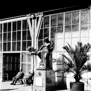 Statue fountain in front of modern building with people resting.