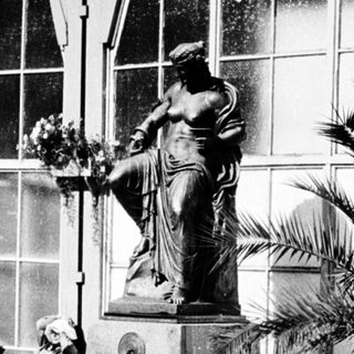 Statue fountain in front of modern building with people resting.