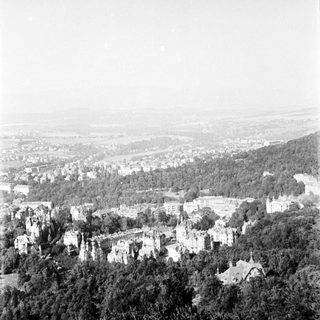 Historic castle ruins overlooking forested valley town.