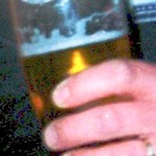 Man drinks beer while young child eats.