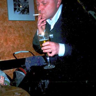 Man drinks beer while young child eats.
