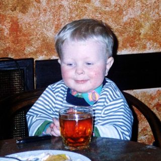 Young child sitting at restaurant table with drink.