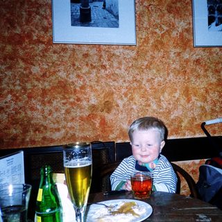 Young child sitting at restaurant table with drink.