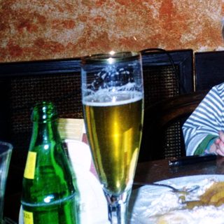 Young child sitting at restaurant table with drink.