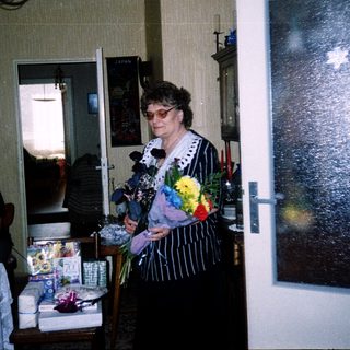Woman speaking at a celebratory indoor gathering with gifts.