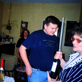 Two adults playfully holding and posing with a wine bottle.