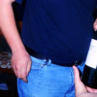Two adults playfully holding and posing with a wine bottle.