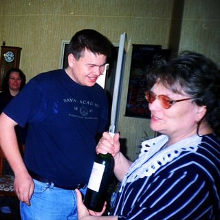 Two adults playfully holding and posing with a wine bottle.