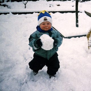 Child playing in snow with snowball.