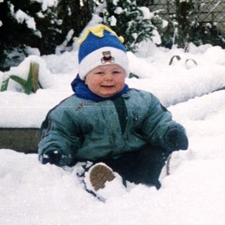 Child playing in snow-covered garden.