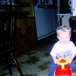 Child sitting on toy wagon indoors.