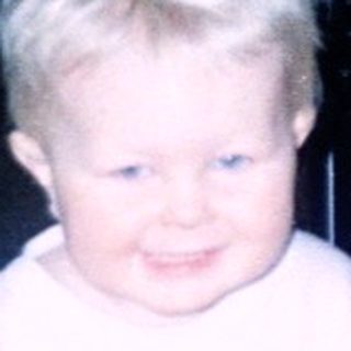 Child sitting on toy wagon indoors.