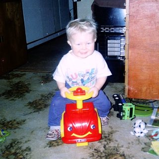 Child sitting on toy wagon indoors.