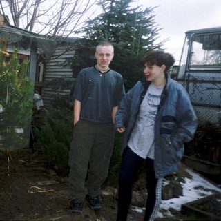 Two people standing beside a burning Christmas tree.