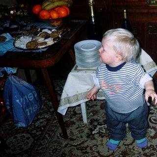 Toddler reaching for food at table.