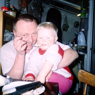 A man and child sharing dessert indoors.