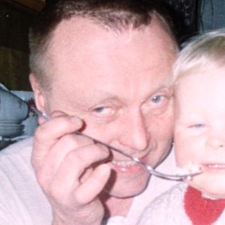 A man and child sharing dessert indoors.