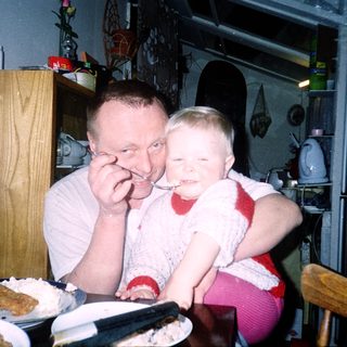 A man and child sharing dessert indoors.