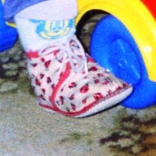 Young child riding red toy car indoors.