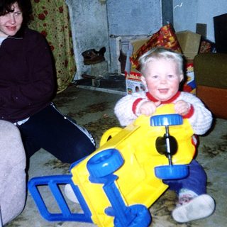 Woman sitting with smiling child in yellow toy.