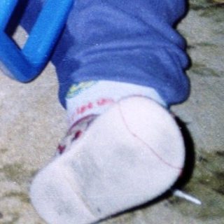 Child playing with yellow and blue toy truck.