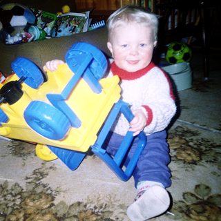 Child playing with yellow and blue toy truck.