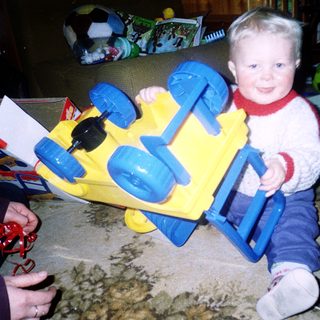 Child playing with yellow and blue toy truck.