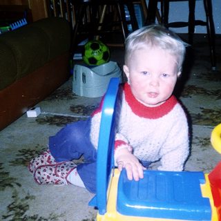 Young child playing with toy truck indoors.