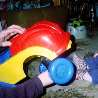 Young child playing with colorful toy car.