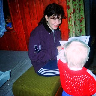Woman reading to a young child indoors.