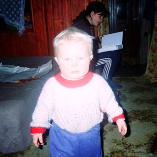 Young child indoors during nighttime, wearing sweater and pants.