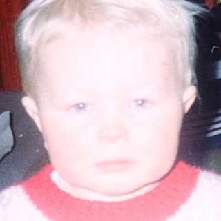 Young child indoors during nighttime, wearing sweater and pants.