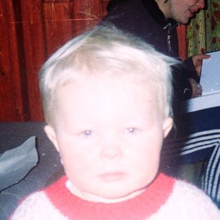 Young child indoors during nighttime, wearing sweater and pants.