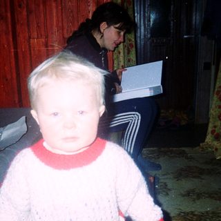 Young child indoors during nighttime, wearing sweater and pants.