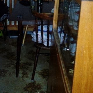 Child standing indoors near woman in dark room.