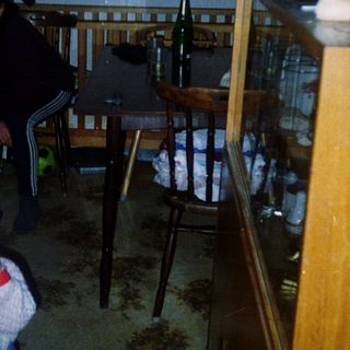Child standing indoors near woman in dark room.