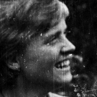 Young woman smiling outdoors in vintage-style photograph.