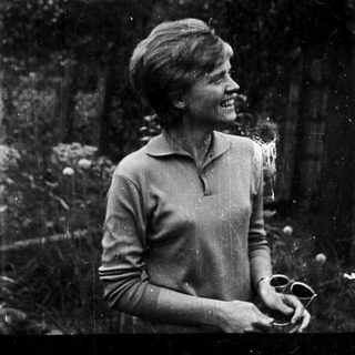 Young woman smiling outdoors in vintage-style photograph.