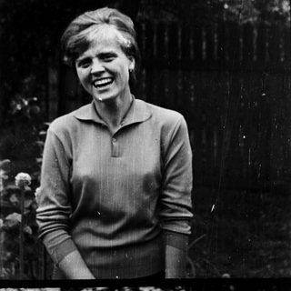 A smiling woman in a sweater outdoors.