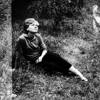 Woman sitting alone in grassy field.