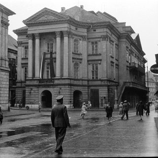 Neoclassical building in urban square, mid-20th century.