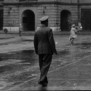 Neoclassical building in urban square, mid-20th century.