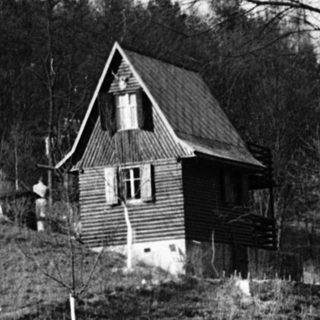 Rural house on elevated, wooded hillside.