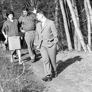 Three men walking on a forest path.