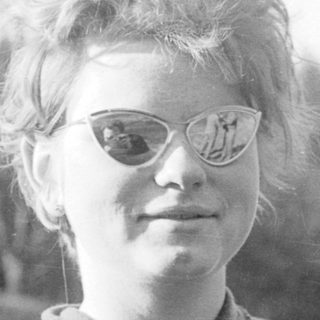 Young woman wearing glasses outdoors in vintage style.